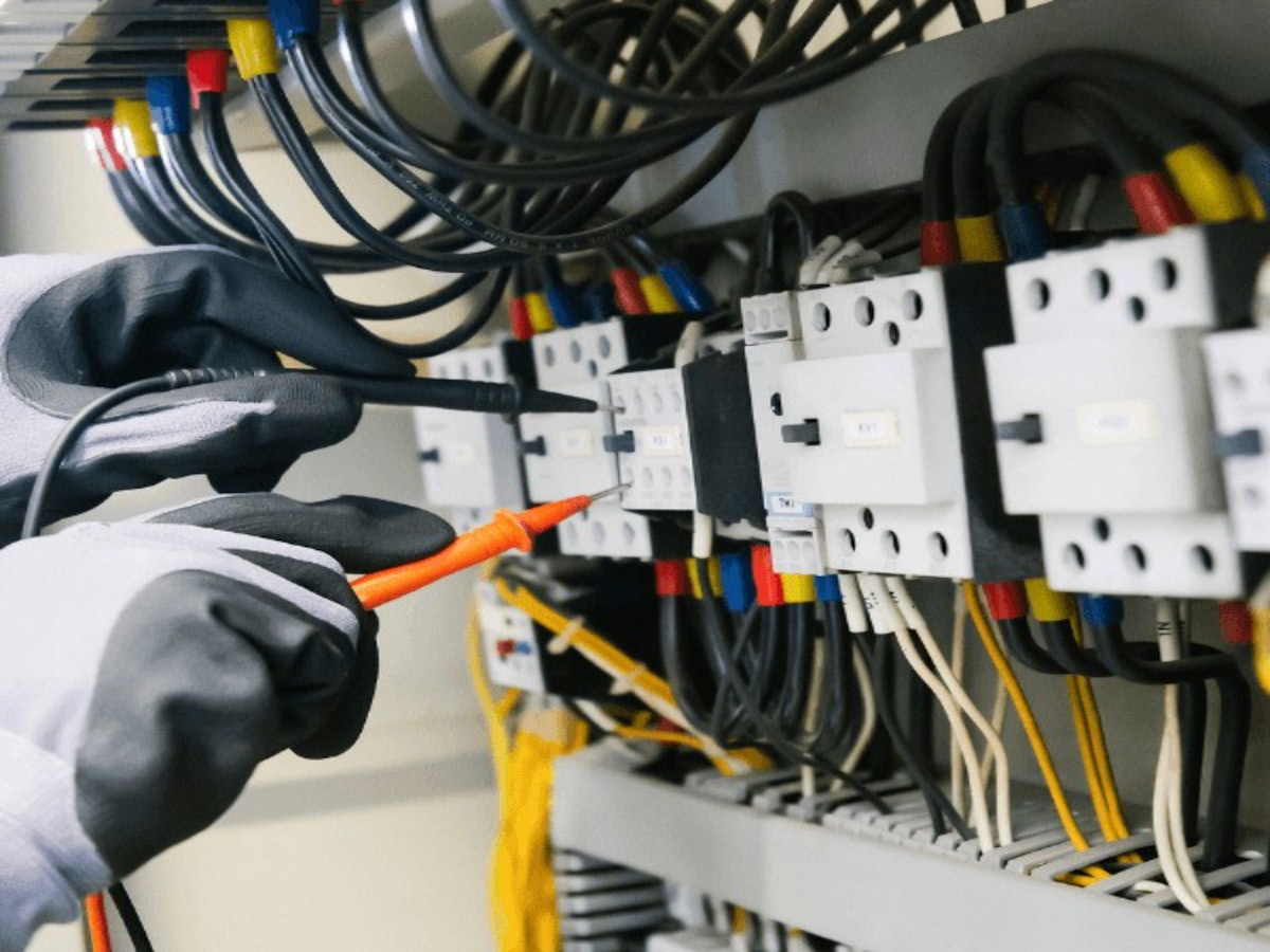 Electrician testing a control panel with a multimeter